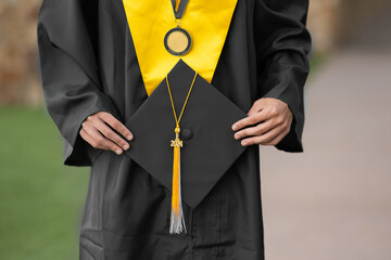 Close up of hands holding graduation cap & medal