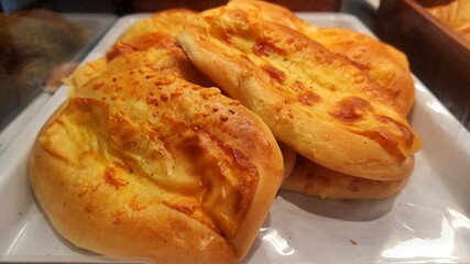 The fresh warm pastry with the cheese on the top displayed on the display rack of bakery shop