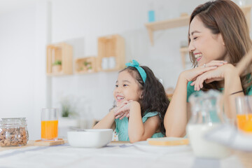 Asian children and her mom have a breakfast in the morning, child nutrition and development, they...