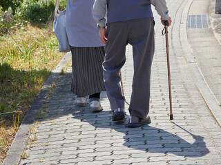 春の昼の街の道で歩くシニア夫婦の姿