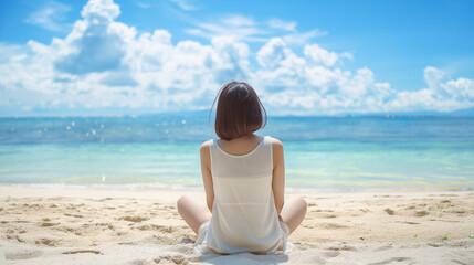 Fototapeta na wymiar 砂浜に座り海の方を見ている若い女性の後姿の明るく美しい写真