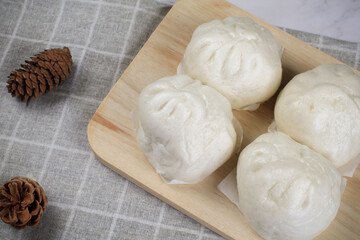 Steamed buns with minced pork on bamboo cutting board. Chinese food dim sum style. Breakfast Asian food.