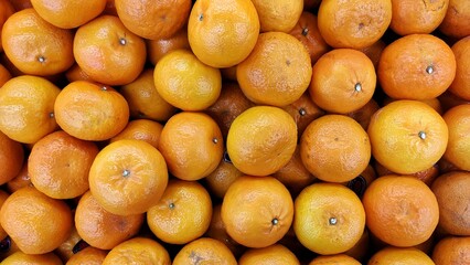A pile of orange fruit displayed in supermarket to attract the customers to buy