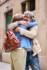 Vertical. Portrait happy older gray-haired man embracing adult woman outdoor. Love hug between retired married couple. Affectionate relationship of pensioner partner. Mature love reunion people