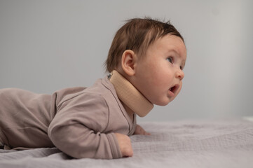 Portrait of a newborn baby lying on his stomach in an orthopedic collar.