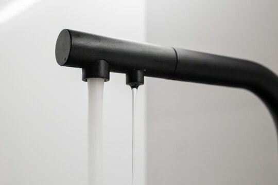 Tap and filtered water flows from the modern kitchen faucet . 