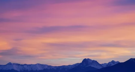 Deurstickers Tramonto luminoso viola arancio e rosa sopra le montagne innevate © GjGj