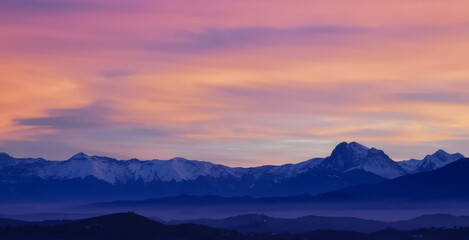 Tramonto luminoso viola arancio e rosa sopra le montagne innevate - obrazy, fototapety, plakaty