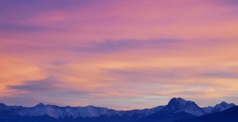 Tramonto luminoso viola e rosa sopra le montagne innevate
