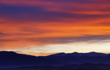 Nuvole rosse al tramonto sulla cime delle montagne