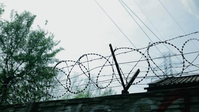 Overview of the electric chain-link fence with barbed wire of the prison on a rainy day. Drops of rain on the fence. High quality FullHD footage