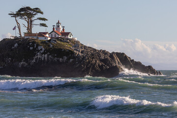 A lighthouse sits on a rocky hillside. The lighthouse is white and red, and it is surrounded by a lush green hillside. The scene is peaceful and serene. Battery Point Lighthouse, California. - 786752659