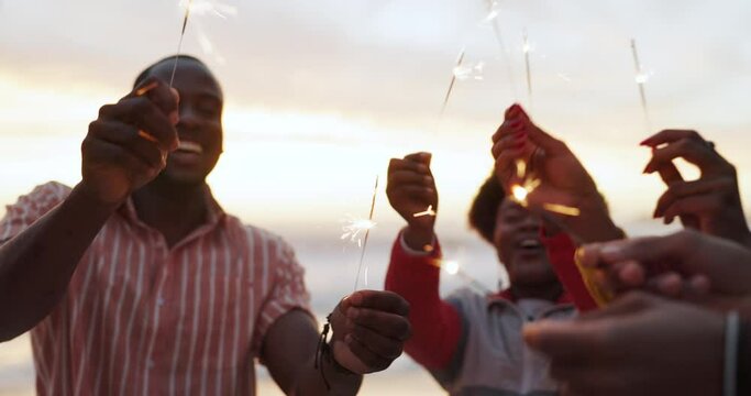 Friends, sparklers and beach celebration with sunset, joy and fun for new year party. People, fireworks and sea with dance, event or birthday with summer holiday and travel or adventure together