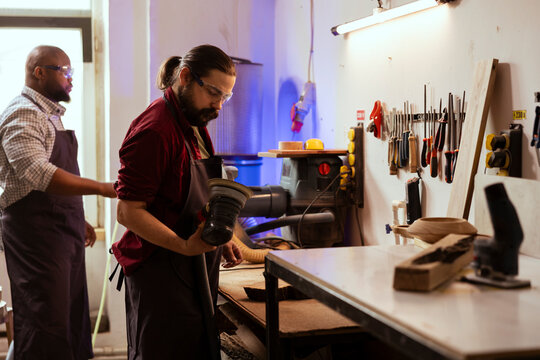 Craftsperson working with orbital sander with fine sandpaper on lumber to achieve smooth finish, checking quality. Woodworking expert in carpentry shop inspecting damaged angle grinder - Powered by Adobe