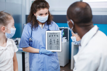 During a visit, bone doctor and nurse discuss the best medical alternatives for the patient in the...