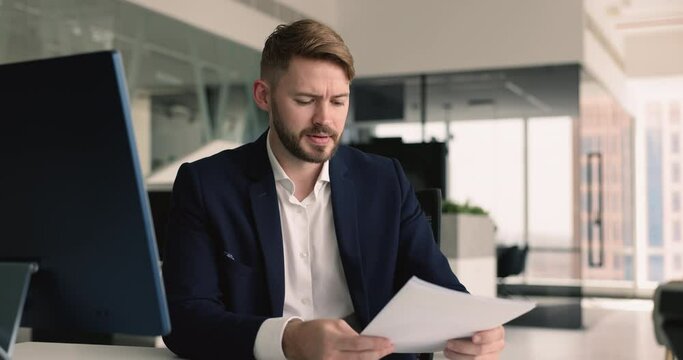 Businessman get bad news related to his business, sit at desk, holds papers, feel stressed about financial setback, investment or revenue loss, failed business deal, negative feedback from clients