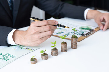 Businessman with coin stack at his office as sustainable money growth investment or eco-subsidize....