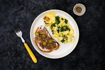 Omelet with spinach leaves with tuna sandwich and cream cheese and salt cucumber.Omelette on plate, scrambled eggs on black background, top view.