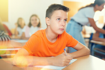 Schoolboy sitting at the desk in classroom at lesson in primary school