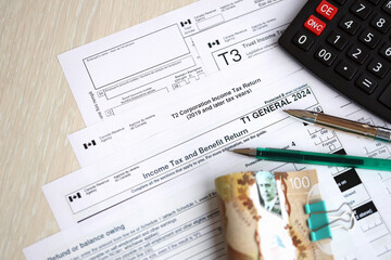 Many blank Canadian tax forms lies on table with canadian money bills, calculator and pen close up....