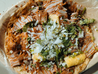 Top view of large plate Mexican al pastor street tacos with cilantro, onion, and pineapple.