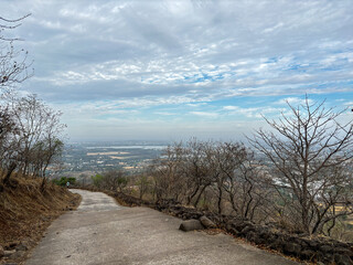 A path winds through a forest with a view of a city in the distance at Ralamandal, Indore, India.