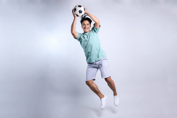 Full Length of  Attractive Young Asian Man Throwing or Catching Soccer Ball Isolated on White...