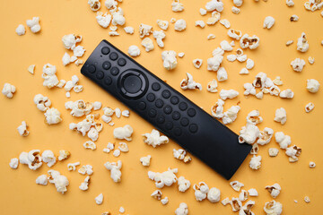 Remote Control with Popcorns Spread on Yellow Background. Movie and Cinema Concept. 