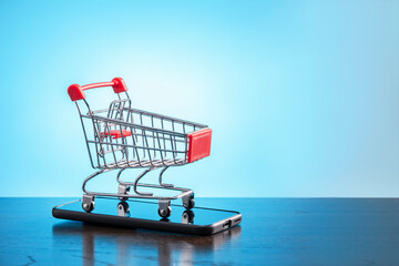 Online shopping concept.  Shopping cart with smartphone for shopping online.