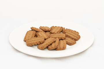 Dark brown sugar sweet biscuits in plate on isolated white background