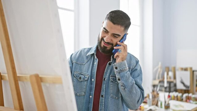 Smiling bearded man talking on phone in a bright art studio