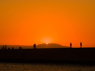 Fototapeta premium Silhouette of people in a port town at dusk (Chania, Crete, Greece)