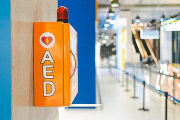 Automated External Defibrillator box AED machine with instructions on the wall in shopping mall.