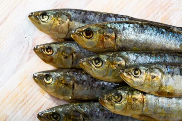 Gordijnen Closeup of stack of salted sardines on wooden background.. © JackF