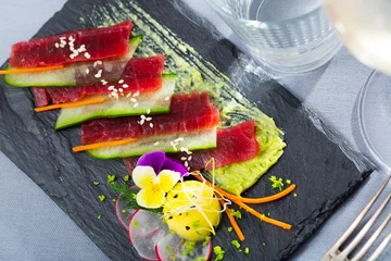 Gordijnen Tuna sashimi served with mango and vegetables on slate © JackF