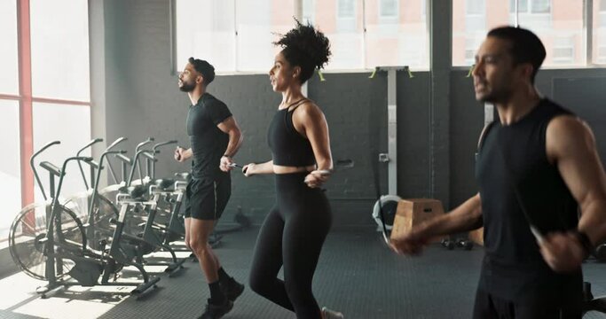 Fitness, skipping rope and group of athletes in gym for health, wellness and body workout. Team, jumping and people and personal trainer with equipment for cardio exercise at class in sports center.