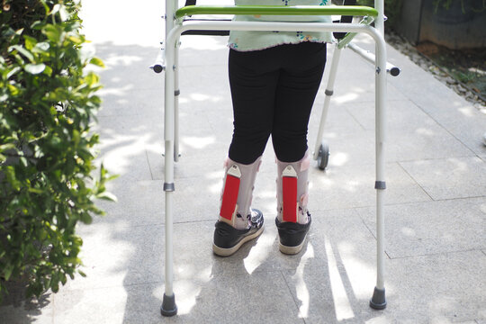  child with walking frame and knee orthosis outdoor 
