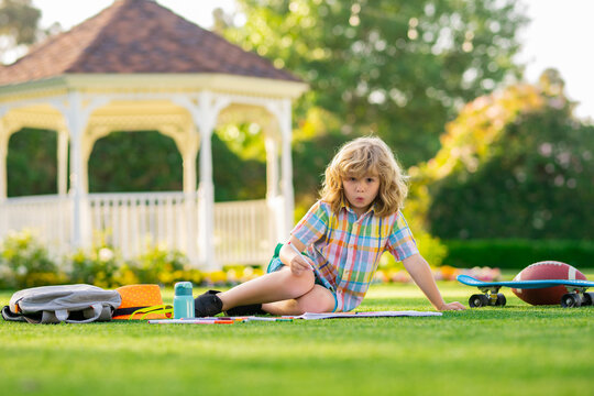 Child drawing picture with crayon in summer park outdoor. Happy little kid boy holding a brush to paint with toys for playing outdoor.