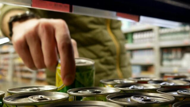 A male buyer takes two soda cans in a grocery store