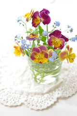 ガラス瓶に挿したパンジーとワスレナグサ