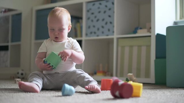 one year old boy  sitting on the floor play in the child's room with montessori tower