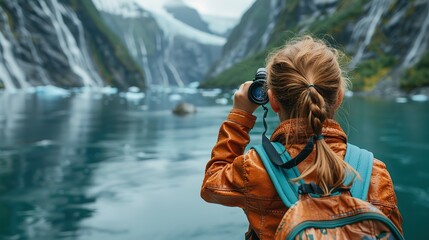 A young girl looks through tourist binoculars toward a fjord in Alaska