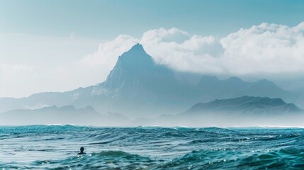 A man is swimming in the ocean near a mountain