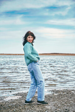 49 year old Russian woman in sweater laughing, looking at the camera on an early spring  day against japanese sea