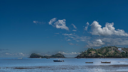 The boats are anchored in the blue ocean. Beautiful islands with green vegetation against a...