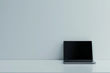 A laptop is open on a table in front of a white wall
