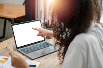 Back view of a businesswoman pointing at a blank laptop screen, implying a presentation or discussion.
