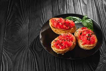 delicious Italian bruschetta with tomatoes on a black wooden rustic background