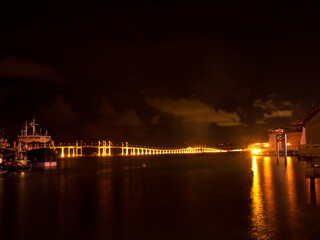 Fototapeta na wymiar Scenic Macau night scenery with illuminated Ponte de Amizade Friendship Bridge and fortress with lights reflecting on water