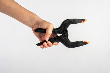Black plastic spring clamp in hand isolated on white background